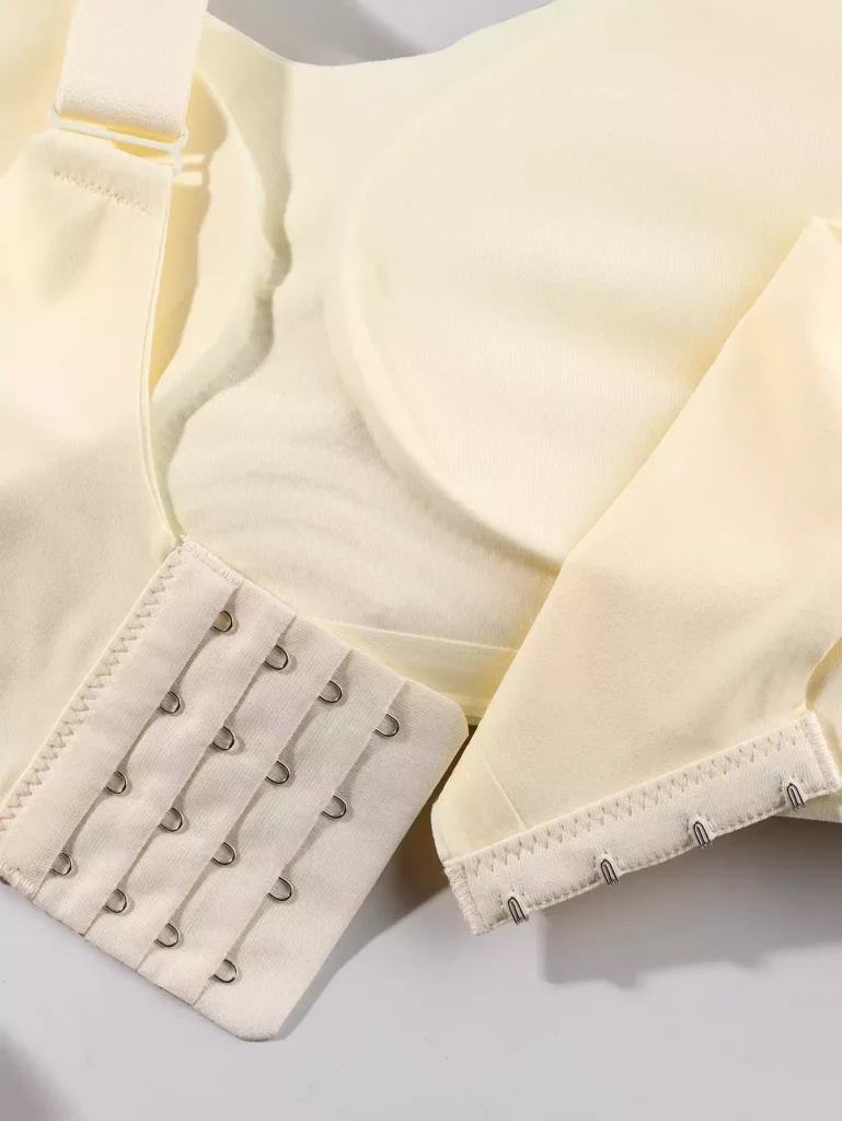 Close-up view of the hook-and-eye closure on a beige seamless bra, showcasing the adjustable strap design and smooth fabric quality.