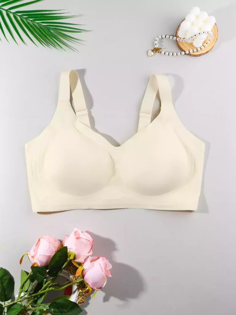 A beige seamless comfort bra displayed on a light background, decorated with artificial roses and a pearl accessory.