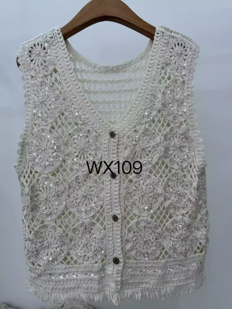 A product hanger shot of a white crochet vest featuring circular floral patterns, button closure, and fringe hem, style WX109.