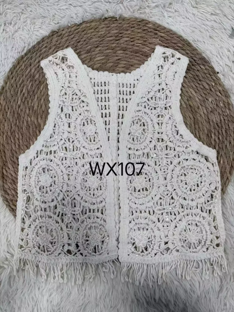 A flat lay product shot of a white floral crochet vest with sequin accents and fringe hem, style WX107.