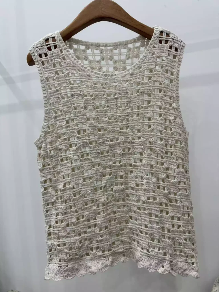 A hanger shot of a white grid-pattern crochet tank top, showcasing a minimalist openwork weave structure.