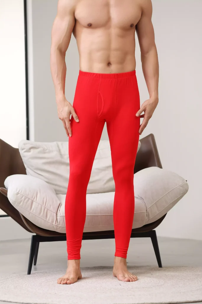 Close-up view of a man wearing red thermal pants, showcasing the ergonomic fit and comfortable waistband of the base layer.