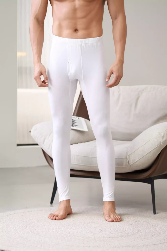 A man wearing white thermal pants, demonstrating the slim, flexible fit and comfortable waistband of the base layer.