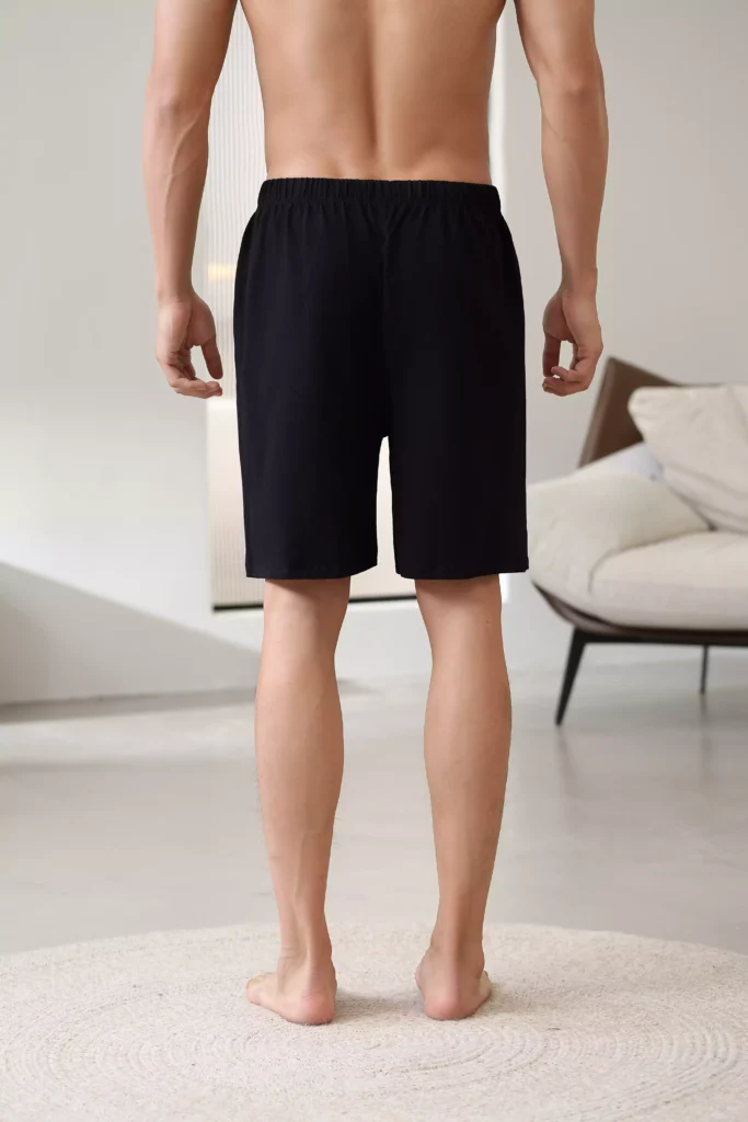 Rear view of a man wearing black casual lounge shorts, showcasing the fit and elastic waistband.