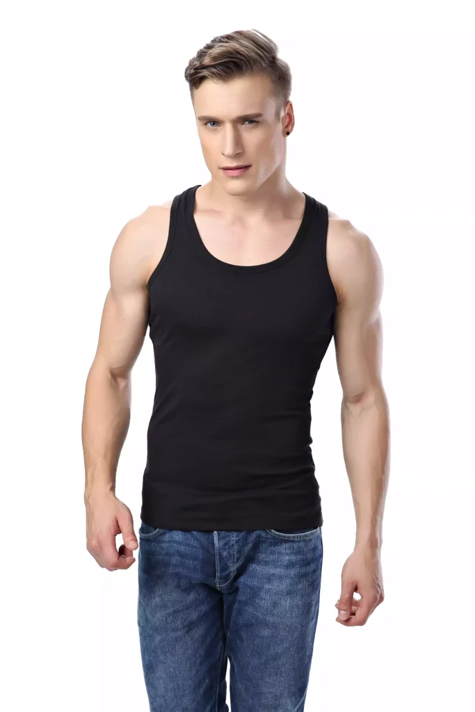 A fit man wearing a stylish black tank top and blue jeans, standing against a clean white background.