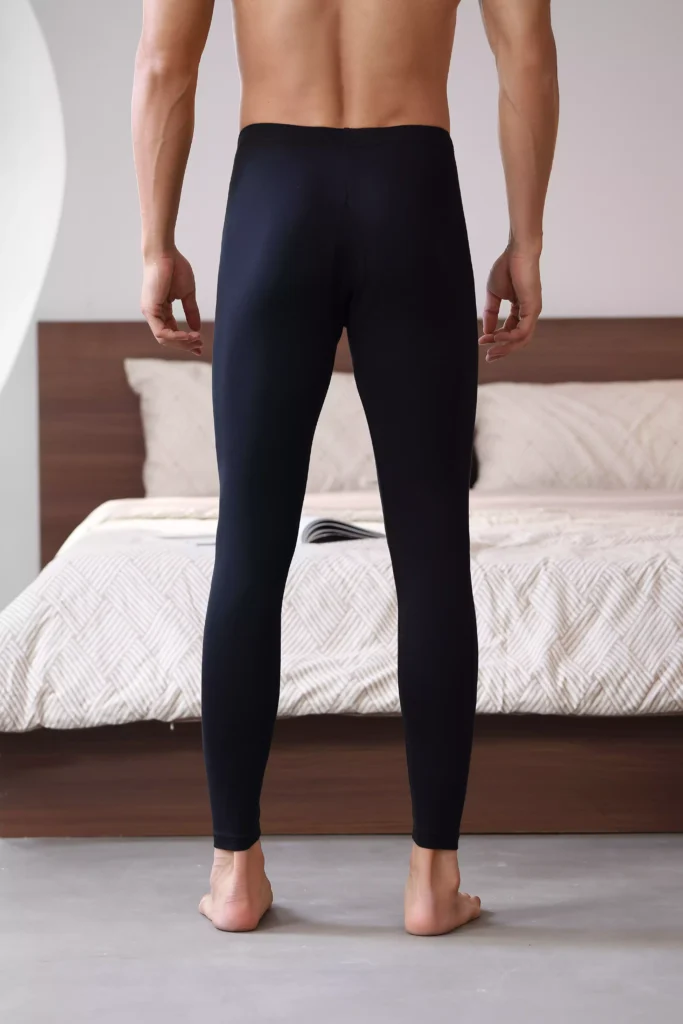 Rear view of a man wearing sleek black thermal leggings, showing a form-fitting, minimalist design ideal for winter layering.