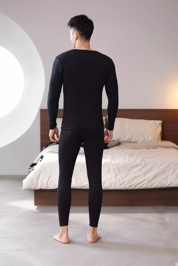 Rear view of a man wearing a black thermal underwear set, highlighting a sleek and tailored fit.