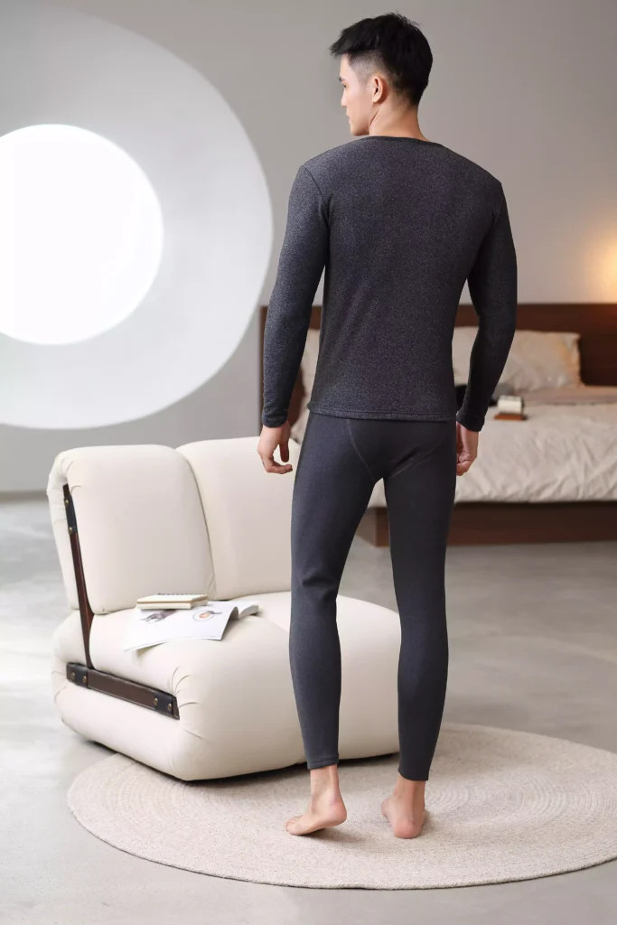 Rear view of a man wearing a dark grey thermal underwear set, highlighting a sleek and tailored fit.