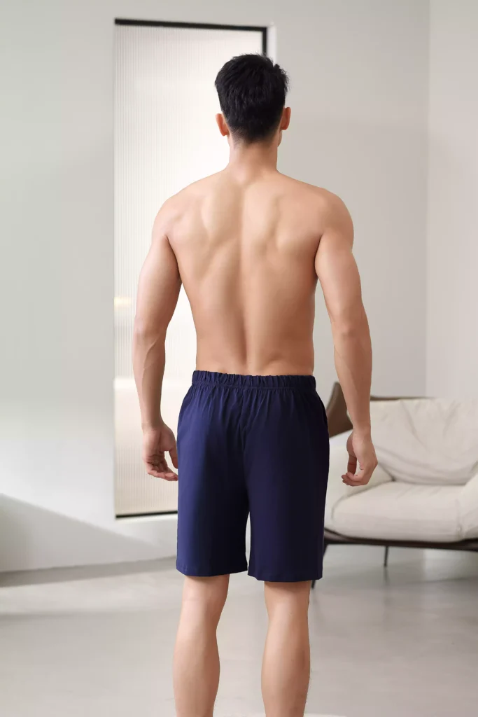 Rear view of a fit man wearing navy blue lounge shorts, showing the comfortable fit and clean back design.
