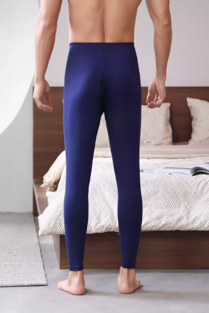 Rear view of a man wearing navy blue thermal leggings, showing a smooth fit and comfortable design for winter layering. •