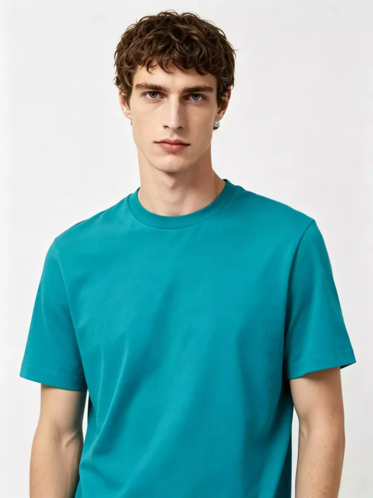Front view of a male model wearing a vibrant peacock blue crew-neck T-shirt, highlighting the clean fit and premium cotton fabric against a neutral studio background.