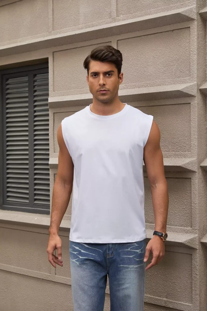 Front view of a man wearing a white sleeveless muscle tee paired with light wash jeans.