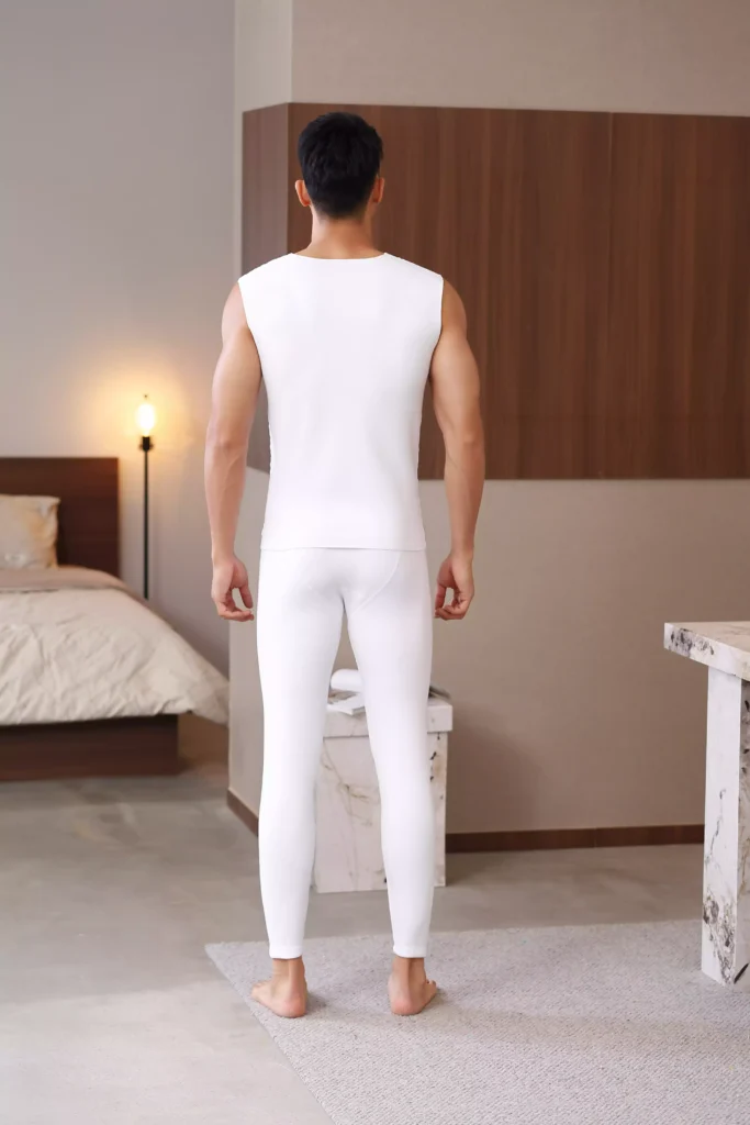 Back view of a man wearing a white sleeveless thermal undershirt and matching thermal leggings, showcasing the sleek and comfortable fit.