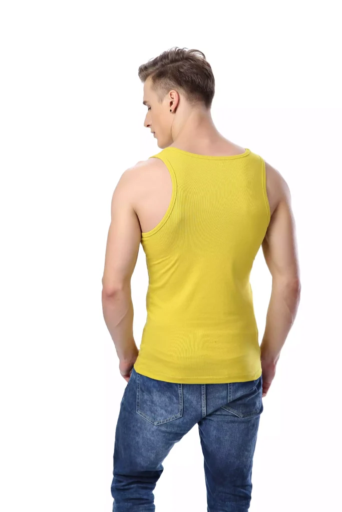 A male model seen from the back, wearing a fitted yellow cotton tank top and blue jeans, showcasing the shirt's cut and fit.