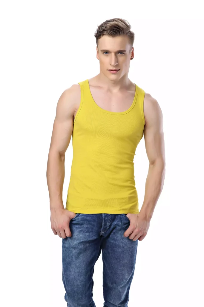 A fit man wearing a vibrant yellow tank top and blue jeans, standing against a clean white background.