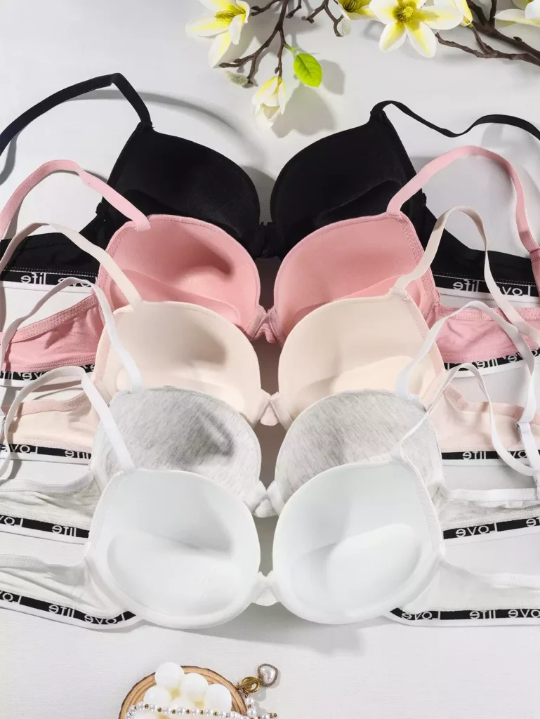Flat lay of a lingerie collection featuring bras in black, pink, nude, grey, and white, showcasing various color options and comfortable design.