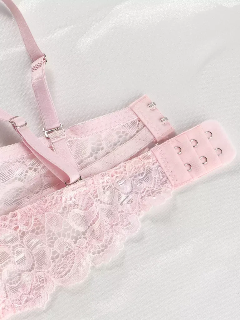 Close-up of the delicate floral lace back wing and adjustable hook-and-eye closure on a light pink bra, showing premium fabric and craftsmanship.