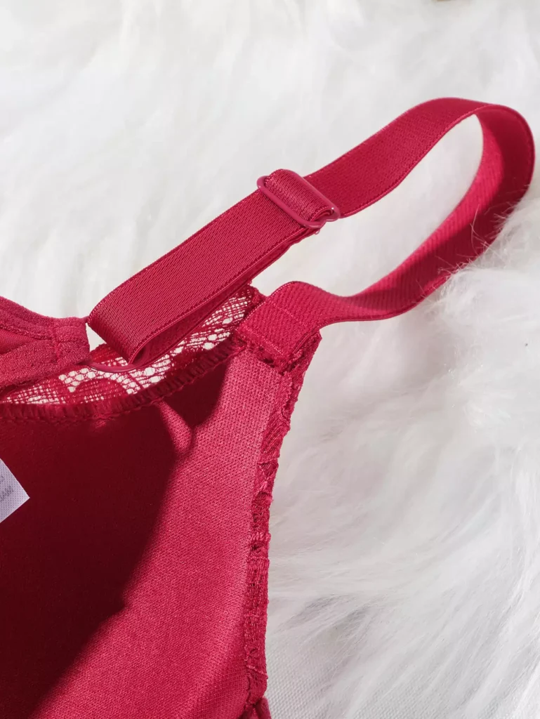 Close-up view of the fine stitching and fabric quality on the strap of a red lace lingerie bra.