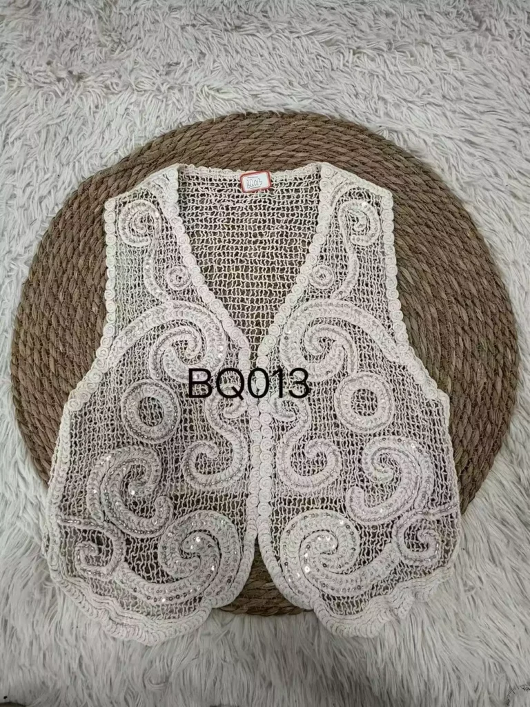 Flat lay product shot of a white swirl-pattern crochet vest, showcasing intricate swirl embroidery, sequin accents, and fine craftsmanship, style BQ013.