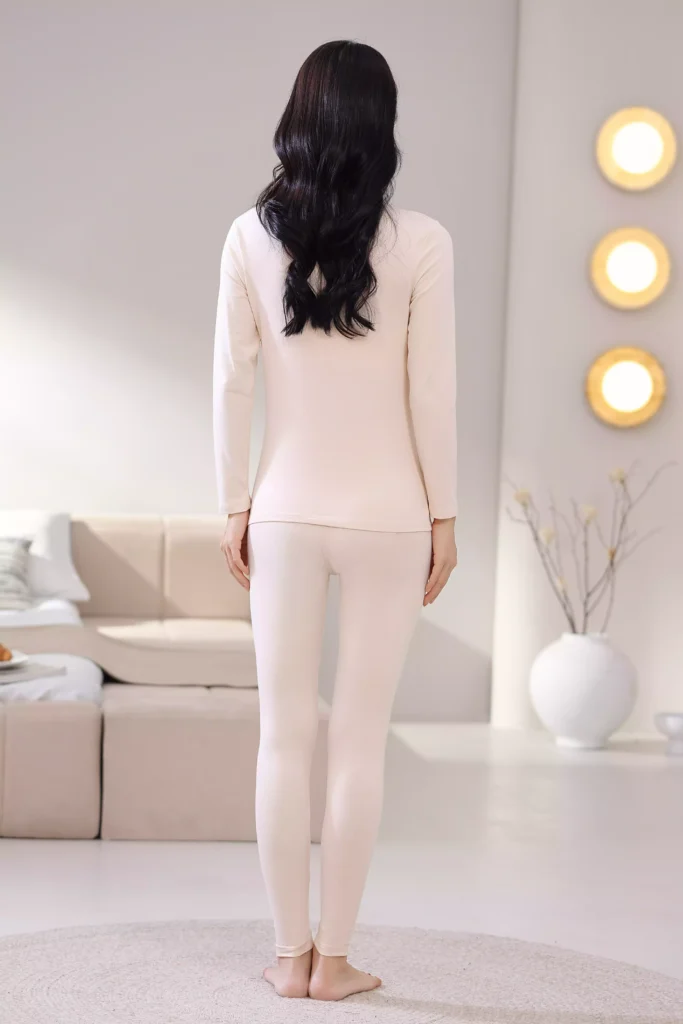 Back view of a woman wearing a beige mock-neck thermal underwear set, showcasing the sleek, slim-fit design and comfortable cut of the long-sleeve top and leggings