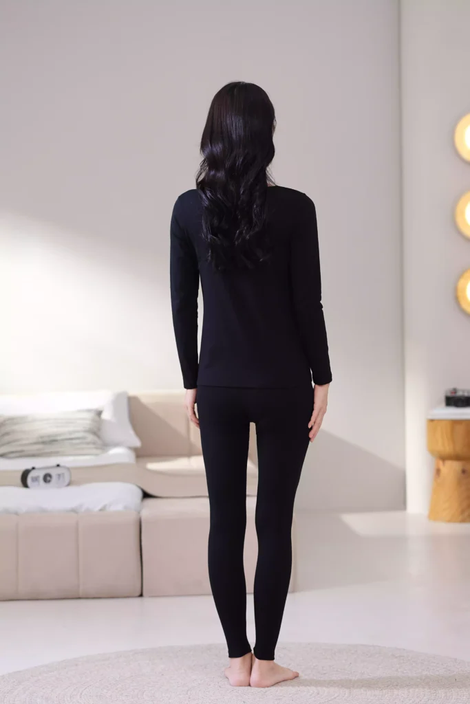 Back view of a woman wearing a black thermal underwear set, demonstrating the sleek, slim-fit design and comfortable cut of the long-sleeve top and leggings.