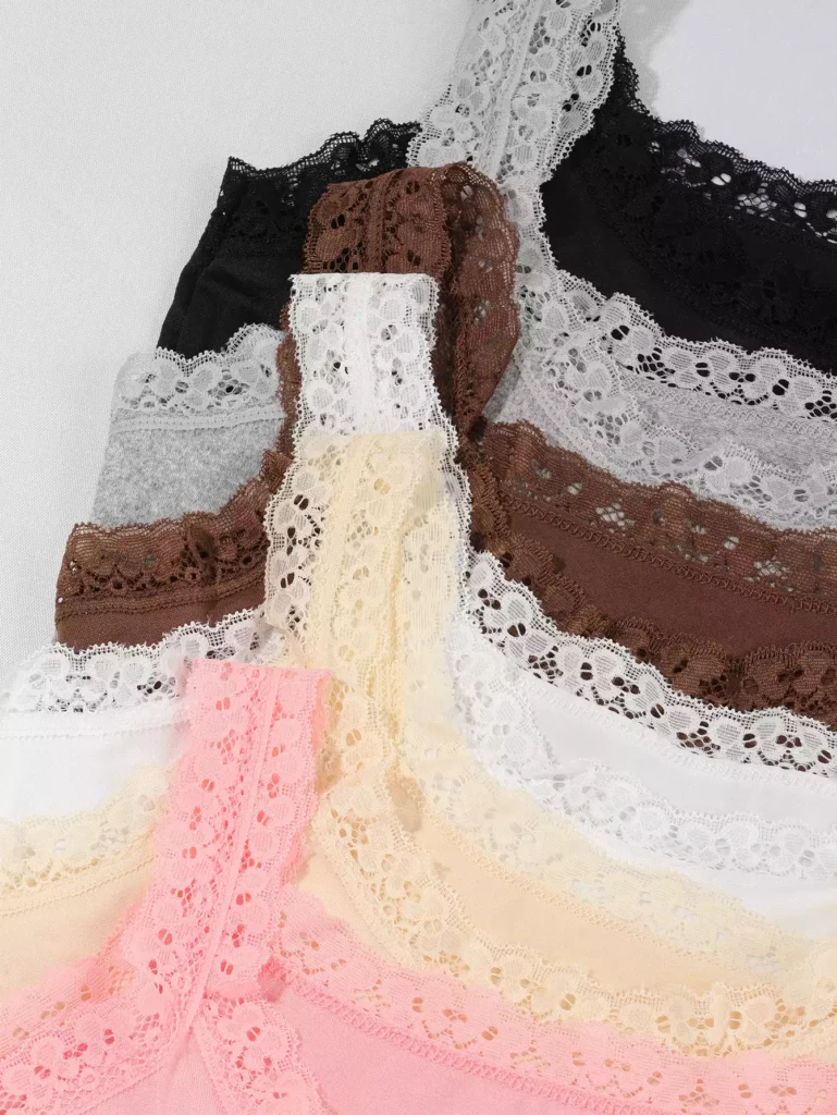 Close-up view of various camisoles stacked together, highlighting the intricate floral lace trim detail in multiple colors.