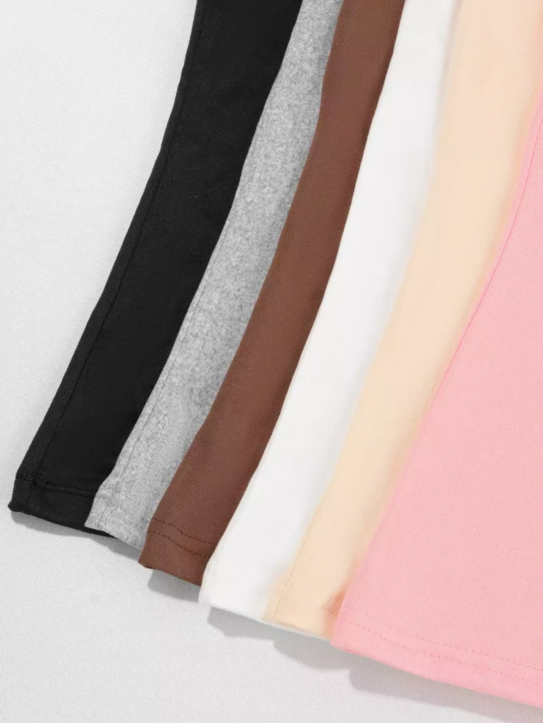 Close-up of folded fabric in various colors including black, grey, brown, white, beige, and pink, showing the cotton texture.