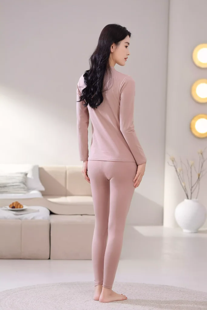 Back view of a woman wearing a dusty pink mock-neck thermal underwear set, showcasing the sleek, slim-fit design and comfortable cut.
