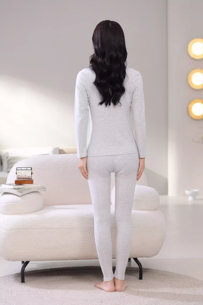Back view of a woman wearing a grey thermal underwear set, showcasing the sleek, slim-fit design and comfortable cut of the long-sleeve top and leggings.