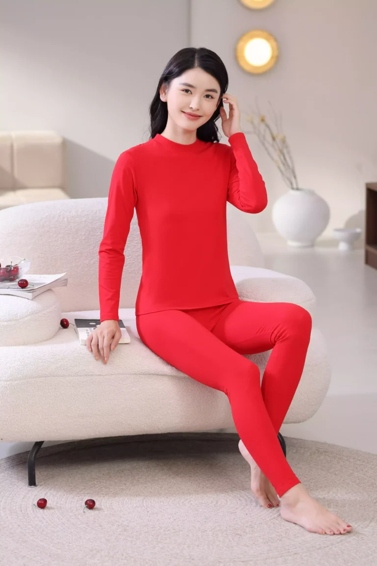 A woman sitting on a sofa wearing a comfortable red long-sleeve thermal loungewear set, demonstrating the soft fit and style.