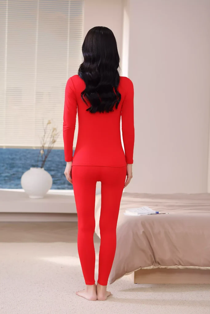 Back view of a woman wearing a vibrant red thermal underwear set, showcasing the sleek, slim-fit design and comfortable cut of the long-sleeve top and leggings.