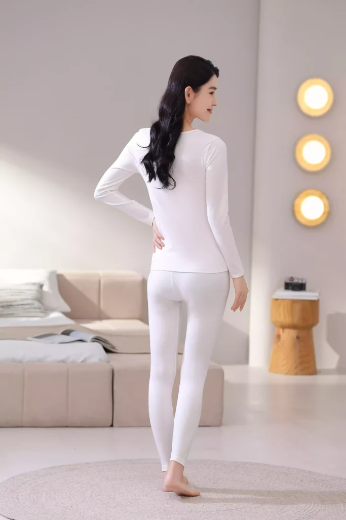 Back view of a woman wearing a white thermal underwear set, showcasing the slim-fit design and comfortable fabric of the long-sleeve top and leggings.